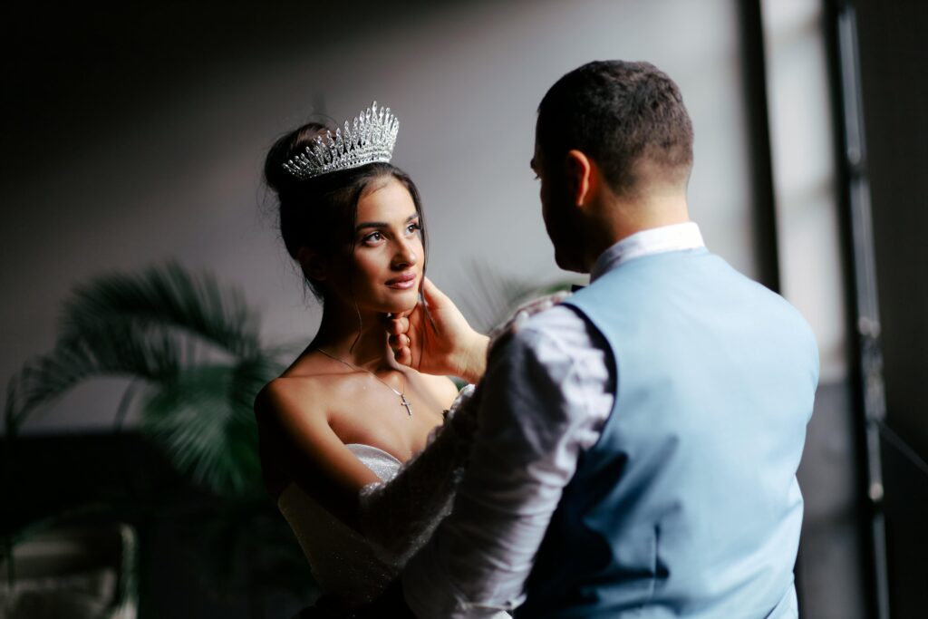 A stunning bride and groom share an intimate moment next to a window, capturing the essence of love and elegance.